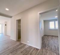 A hallway in a family house with a wooden decor floor and light-colored walls.