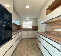 A kitchen in a family house with a wooden decor floor and white cabinets.
