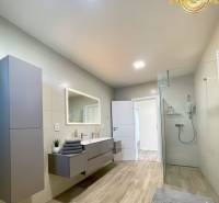 Bathroom with wood-patterned flooring, shower enclosure, and furniture in a family house.