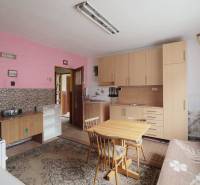 A kitchen in a family house with pink walls and simple wooden furniture.