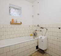 Bathroom in a family house with a bathtub and a gas boiler, tiled with white tiles.