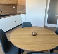 A kitchen in a studio apartment with a wooden-patterned floor and a modern dining table.