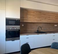 A kitchen with white cabinets and a wood-patterned floor in a studio apartment.