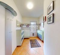 A hallway in a family house with tiles, furniture, and paintings on the walls.