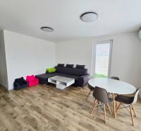 Living room of a family house with a wooden decor floor, gray sofa, and round table.