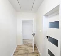 A hallway of a family house with a wooden-patterned floor and white doors.
