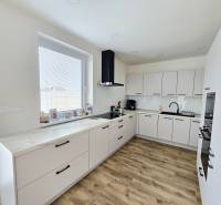 A kitchen in a family house with white cabinets and a wood-patterned floor.