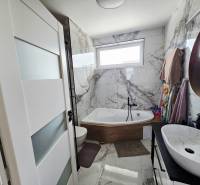 Bathroom with a mirror, bathtub, and marble tiles in a family house.