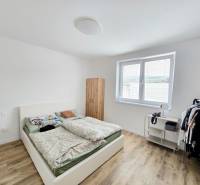 Bedroom with a bed, wardrobe, and wood-decorated floor in a family house.