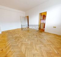 Living room in a two-room apartment with a wooden decor floor and a large window.