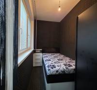 Narrow bedroom in a studio apartment with a floral mattress and black walls.