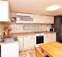 A kitchen with light cabinets, a sink, and a table with wood-patterned flooring in Gardens.