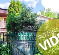 A house surrounded by greenery in the gardens of Bernolákovo, wooden fence and balcony.