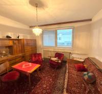 Obývacia izba v rodinnom dome s červenými kreslami, lustrom a dreveným nábytkom.