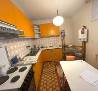 Kuchyňa v rodinnom dome s výraznými oranžovými skrinkami a retro dlažbou.