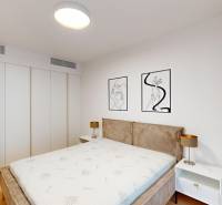 Bedroom in a 2-room apartment with a bed, art on the wall, and nightstands.