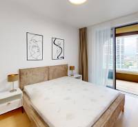 Bedroom in a 2-room apartment with a bed, nightstands, and a balcony, floor with wooden decor.