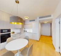 A kitchen in a 2-room apartment with white furniture and a wooden decor floor.