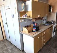 A kitchen in a 3-room apartment with a countertop and doors, floor with wood decor.