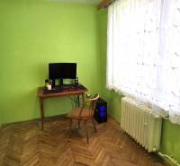 A room in a 3-room apartment with a wooden decor floor, a table, and a computer.