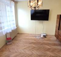 Living room with a TV, display cabinet, and wooden decor flooring in a 3-room apartment.