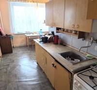 A kitchen in a 3-room apartment with a simple kitchenette, seating, and shelves.