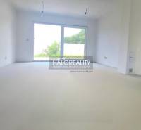 A spacious room with a large window in a family house, white walls, view of the garden.