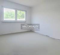 A spacious room with white walls and a large window in a family house.