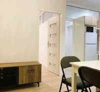 Interior of a 3-room apartment with a dining table, folding chair, and wooden decor of a sideboard.