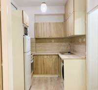 A kitchen in a 3-room apartment with wood-patterned flooring and light-colored furniture.