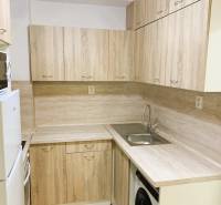 A kitchen unit in a 3-room apartment with a wooden decor and built-in appliances.