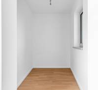 A small room with white walls and a floor with a wooden decor in a 4-room apartment.
