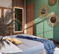 A bedroom in a one-room apartment with decorative mirrors, a green wall, and natural elements.