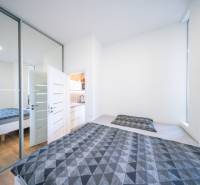 A bedroom in a 2-room apartment with a bed, a mirrored wardrobe, and a floor with a wooden decor.