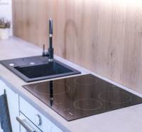 A kitchen in a 2-room apartment with an induction cooktop and a floor with a wooden decor.