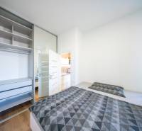 Bedroom in a 2-room apartment with a bed, wardrobe, and floor with a wooden decor.