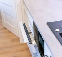 A kitchen with a dishwasher and a wooden decor floor in a 2-room apartment.