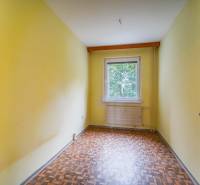 A room with a window, yellow walls, a floor with a wooden decor in a 3-room apartment.