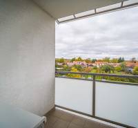 A balcony with a view of rooftops and greenery in a 3-room apartment on Komenského Street, Modra.