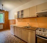 A kitchen in a 3-room apartment with a gas stove and a floor with a wooden decor.