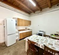 Dining table and kitchen with a white refrigerator and stove in a family house.
