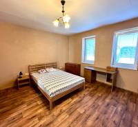 A bedroom in a family house with a bed, a table, and a floor with a wooden decor.