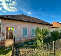 A family house in Ludanice with fencing and a simple facade, with a blue sky in the background.