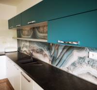 A kitchen in a 3-room apartment with a striking wall and a wooden decor floor.