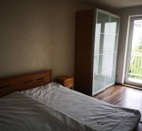 A bedroom in a 3-room apartment with a bed, wardrobe, and floor with a wooden decor.