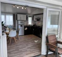 An interior with a light table, chairs, kitchen unit, and a floor with a wooden decor.