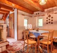 The interior of a cottage with a tiled stove, wooden furniture, and decorations on the walls.