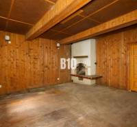 Interior of a cabin with wooden walls, floor, and fireplace.