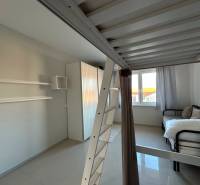 A room with a bunk bed, a bed, white curtains, and storage space in a 3-room apartment.