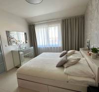 A bright bedroom with a large bed and a mirrored dresser in a 3-room apartment.